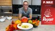 Koch Peter Lehner präsentiert lächelnd in einer modernen Küche das fertige Gericht. Vor ihm steht ein Teller mit cremiger Kürbissuppe und einem Stück Kürbisstrudel, umgeben von dekorativen Kürbissen und Herbstlaub.