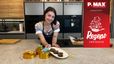 Patissiere Sarah Jahn präsentiert in einer modernen Küche die fertigen veganen Kokosnuss-Brownies auf einem Teller. Daneben sind auch die zubereiteten Toffees in kleinen Förmchen auf der Arbeitsplatte angerichtet.