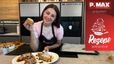 Patissière Sarah in einer modernen Küche, die das fertige Rezept präsentiert. Sie hält ein mit Mandelcreme gefülltes Croissant in die Kamera, während auf einem Teller vor ihr weitere Croissants mit Mandel- und Heidelbeercreme angerichtet sind.