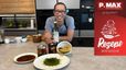 Chefkoch Peter Lehner präsentiert lächelnd in einer modernen Küche die Gerichte des Rezepts der Woche. Er hält eine Flasche Kürbiskernöl, und vor ihm auf der Arbeitsplatte sind der Käferbohnen-Hummus mit Kräutern, das Kernöl-Flatbread und Gläser mit sauer eingelegtem Gemüse angerichtet.