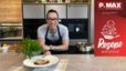 Chefkoch Peter Lehner präsentiert lächelnd das fertige Gericht in einer modernen Küche. Im Vordergrund ist ein Teller mit einer Scheibe Schweinsfilet im Strudelteig zu sehen, das auf einem Bett aus Bohnen-Cassoulet angerichtet und mit frischen Kräutern garniert ist.