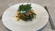 Ein knuspriger Rösti, belegt mit grünem Spargel, Räucherlachs und einem pochierten Ei. Das Gericht ist mit frischer Kresse garniert und auf einem weißen Teller angerichtet.