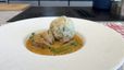 Servierfertiges Kalbsrahmgulasch in cremiger Sauce mit zarten Fleischstücken und einem großen Semmelknödel auf einem weißen Teller. Das Gericht ist mit frischer Petersilie und einer Essiggurke garniert.