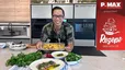 Peter Lehner präsentiert lächelnd in einer modernen Küche eine Auflaufform mit goldbraun überbackenem Macaroni-Mais-Gratin. Im Vordergrund steht ein Teller mit tranchiertem Steak, das mit frischem, grünem Chimichurri garniert ist, umgeben von Schalen mit frischen Kräutern.